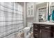 Bathroom with a shower-tub combo, a striped curtain, and dark cabinets at 7991 Heritage Dr, Thornton, CO 80602