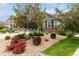 Landscaped front yard featuring flowering bushes, mature trees, decorative rocks, and healthy lawn, creating curb appeal at 7991 Heritage Dr, Thornton, CO 80602