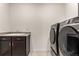 Laundry room features grey front load washer and dryer and utility sink with storage at 7991 Heritage Dr, Thornton, CO 80602