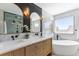 Beautiful primary bathroom featuring a double sink vanity, free standing tub and a large window at 8369 W Fairview Ave, Littleton, CO 80128