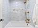 Bright bathroom with a white tub, gold fixtures, and stylish gray tiling with a unique design at 8369 W Fairview Ave, Littleton, CO 80128