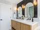 A gorgeous bathroom features double sinks and oval mirrors with modern lighting at 8369 W Fairview Ave, Littleton, CO 80128