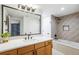 Bright bathroom with a wood vanity, large mirror, and a shower-tub combination at 8369 W Fairview Ave, Littleton, CO 80128