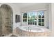 A luxurious bathroom with marble finishes, a soaking tub under a window, and a glass-enclosed shower at 1991 E Alameda Ave # 14, Denver, CO 80209