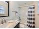 Bathroom with marble vanity top, shower/tub combo, white tile and striped curtain at 3597 Xanthia St, Denver, CO 80238