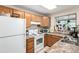 Functional kitchen featuring wooden cabinets, a white refrigerator, and a window with plants at 4636 S Dillon Ct # B, Aurora, CO 80015