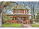 Stunning red brick two-story home featuring a covered front porch, landscaped yard, and charming architectural details at 835 Niagara St, Denver, CO 80220