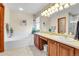 Bathroom featuring a soaking tub, vanity with double sinks, white tile, and wood cabinets at 1339 Bent Grass Cir, Castle Rock, CO 80109