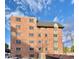 Exterior shot of a multi-story brick apartment building under a bright sky at 1243 Gaylord St # 302, Denver, CO 80206