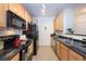 Efficient kitchen with stainless steel sink, black appliances, warm wood cabinets, and tile flooring at 3100 Blue Sky Cir # 205, Erie, CO 80516
