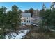Picturesque aerial view of a stunning home surrounded by mature trees and manicured lawns at 6857 Timbers Drive, Evergreen, CO 80439