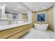 Modern bathroom with wood cabinets, soaking tub, marble floors, and light walls at 6857 Timbers Drive, Evergreen, CO 80439