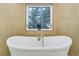 Contemporary soaking tub with gold faucet and large window, wood wall and tile floor at 6857 Timbers Drive, Evergreen, CO 80439