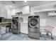 Updated laundry room boasts granite tile flooring, shelving, and stainless steel machines at 6857 Timbers Drive, Evergreen, CO 80439