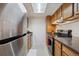 Galley kitchen featuring wooden cabinets, modern stainless steel appliances, and black countertops at 12108 Melody Dr # 103, Denver, CO 80234