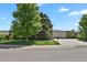 The exterior of the one-story home boasts a two-car garage, concrete driveway, and mature shade trees on the lawn at 5030 Titan Ct, Denver, CO 80239