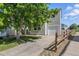 Two-story home with gray siding, front lawn with a large tree, and a driveway leading to an attached garage at 11898 W Tufts Pl, Morrison, CO 80465