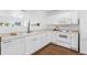 Well-lit kitchen with white cabinetry, updated appliances, and stylish hardwood floors; open to the living area at 11898 W Tufts Pl, Morrison, CO 80465