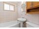 Bathroom with white tile, a pedestal sink, tub, and wooden cabinet at 256 King St, Denver, CO 80219