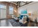 Open living room boasts exposed brick wall, modern furnishings, and concrete flooring at 1111 Osage St # 29, Denver, CO 80204