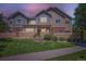 Charming townhouse with a well-maintained lawn, stone accents, and warm exterior lighting at 12856 Jasmine St # E, Thornton, CO 80602