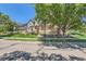 Inviting street view of townhomes featuring stone accents, manicured lawns, and mature trees at 12856 Jasmine St # E, Thornton, CO 80602