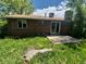 Brick home featuring a sliding door and concrete patio in overgrown backyard at 867 S Grape St, Denver, CO 80246