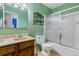 Bathroom with green walls, shower over tub, vanity, toilet and black metal shelf at 12014 E Mexico Ave, Aurora, CO 80012