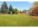 Large, grassy backyard with mature trees, a storage shed, and wooden fence at 7404 La Quinta Ln, Lone Tree, CO 80124