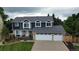 Attractive two-story home features a three-car garage, blue siding, and brick accents, surrounded by lush greenery at 7404 La Quinta Ln, Lone Tree, CO 80124