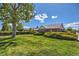 Brick home with manicured green lawn and mature trees, complemented by a bright blue sky with clouds at 2361 Olive St, Denver, CO 80207