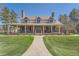 Stunning home showcasing lush greenery, a brick facade, and an inviting covered front porch at 38666 County Road 21, Elizabeth, CO 80107