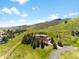 Aerial view of luxury home with mountains, trees, and sprawling lawns under blue skies at 6634 Window Rock Ln, Morrison, CO 80465