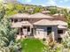 Sweeping aerial shot of a grand home nestled among mature trees and a lush green lawn at 6634 Window Rock Ln, Morrison, CO 80465