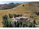 Luxury home with a terracotta tile roof surrounded by evergreen trees and grassy hillsides at 6634 Window Rock Ln, Morrison, CO 80465