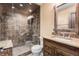 Bathroom featuring a stone and glass shower and wooden sink vanity with matching wooden framed mirror at 6634 Window Rock Ln, Morrison, CO 80465