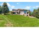 Expansive backyard featuring lush green grass leading up to a large home with many windows at 6634 Window Rock Ln, Morrison, CO 80465