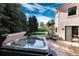 Relaxing hot tub on a stone patio with green grass, trees, and a charming home exterior backdrop at 6634 Window Rock Ln, Morrison, CO 80465