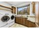 Well-lit laundry room with a washer, dryer, granite countertops, and wooden cabinets at 6634 Window Rock Ln, Morrison, CO 80465