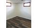 A view of a basement featuring wood-look flooring, two small windows and freshly painted white walls at 609 S 1St Ave, Brighton, CO 80601