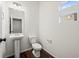 Clean half bathroom with pedestal sink, toilet, and a small window exudes a modern minimalist aesthetic at 10185 Xanadu St, Commerce City, CO 80022