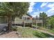 Two-story home with wooden deck surrounded by lush grass, trees, and blue skies at 20410 Brookmont Rd, Morrison, CO 80465