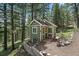 View of a charming green outbuilding surrounded by trees, grass, and lush landscaping at 20410 Brookmont Rd, Morrison, CO 80465