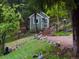 View of a charming green outbuilding surrounded by trees, grass, and lush landscaping at 20410 Brookmont Rd, Morrison, CO 80465