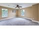 Spacious bedroom featuring a ceiling fan, two windows, and neutral carpeting at 3525 Rinn Valley Dr, Longmont, CO 80504