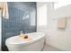 Luxurious bathroom features a freestanding tub with blue tile accent wall and plantation shutters at 2658 Wolff St, Denver, CO 80212