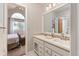 Bright bathroom with double vanity, mirror, and view into a bedroom with a high, vaulted window at 8150 Tempest Ridge Way, Parker, CO 80134