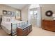 Bedroom with neutral walls and a large window; features a metal bed, chest, dresser, and decorations at 8150 Tempest Ridge Way, Parker, CO 80134