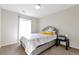 Bright bedroom features a full bed with neutral colored bedding, a side table, and a window with curtains at 12217 Skywalk St, Parker, CO 80134