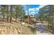 A rustic house surrounded by trees and hillside is shown in this scenic daytime view at 24699 Us Hwy 40, Golden, CO 80401